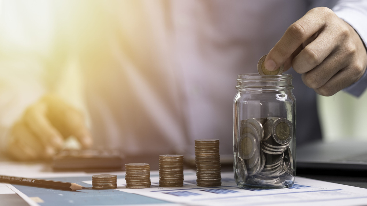 Businessman putting coin to saving jar and use calculator. Money