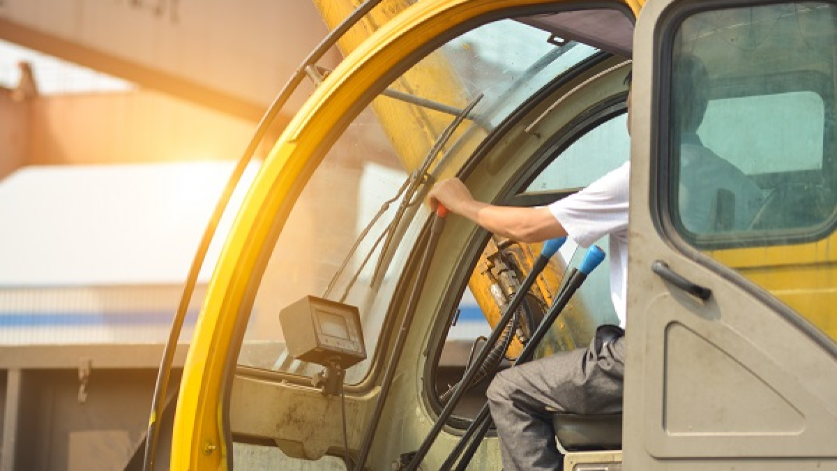 Man driving a crane to lift-up some equipments