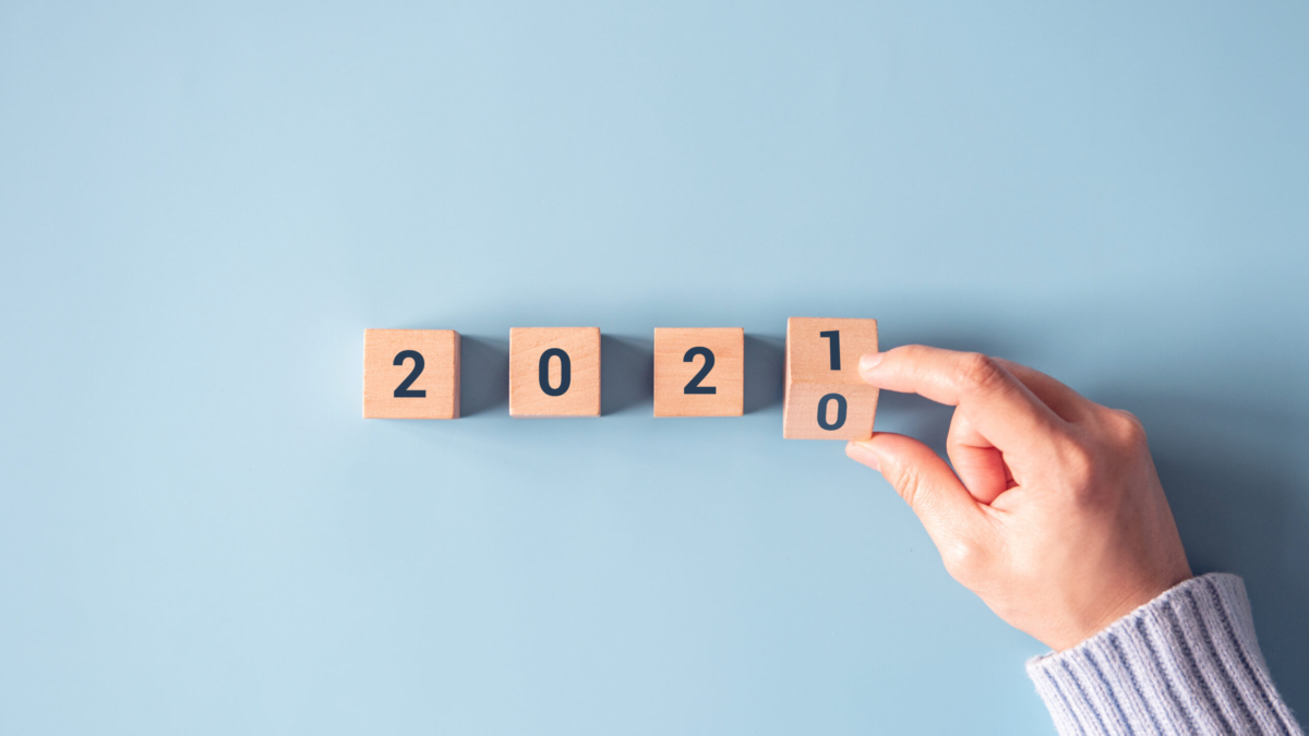 hand-flipping-wooden-blocks-change-year-2020-2021-blue-paper-background